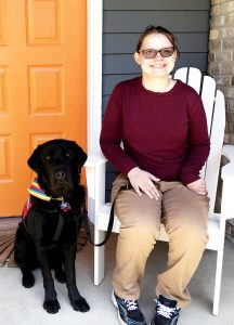 black lab dog and young woman sitting on porch