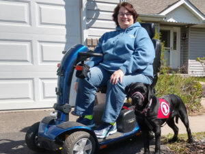 woman in a motorized wheelchair with assistance dog outside of the home
