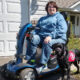 woman in a motorized wheelchair with assistance dog outside of the home