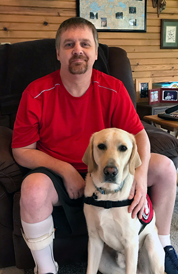man sitting in chair with labrador dog sitting on floor