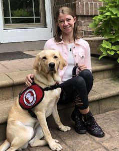 yellow lab service dog with young woman on front steps