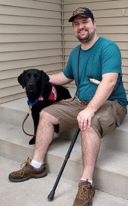 black lab service dog and man sitting on front steps