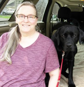 woman and black dog sitting in back of minivan