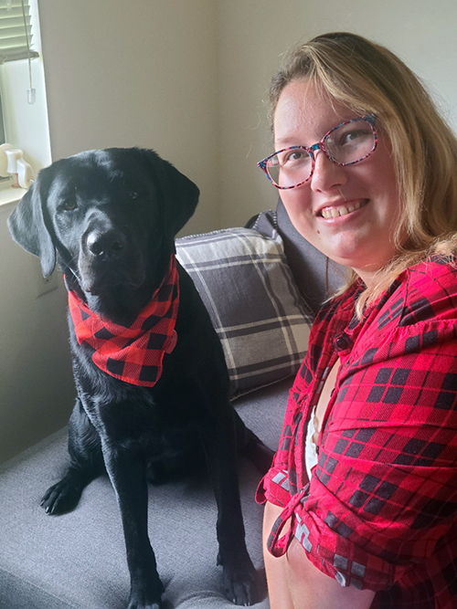 black dog wearing bandana and woman in red and black shirt