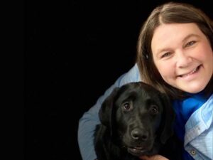 woman poses with a black lab