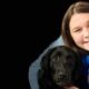 woman poses with a black lab
