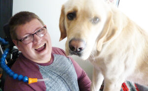 young man laughing with large white dog