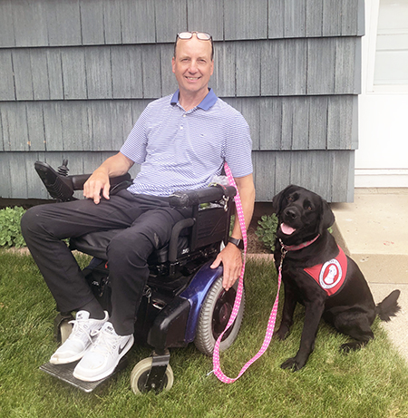 man using a wheelchair next to a service dog