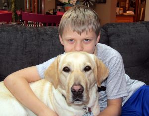 boy hugging yellow lab dog from behind