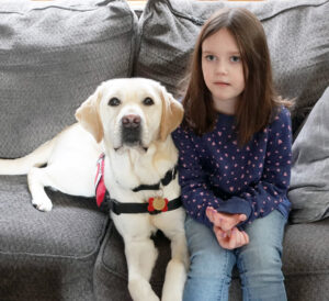 young girl and service dog sitting on couch