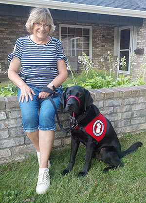 woman and black service dog sitting outside