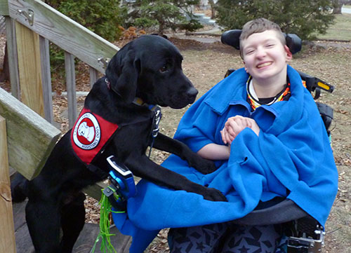 black Lab service dog and teenage boy sitting outside