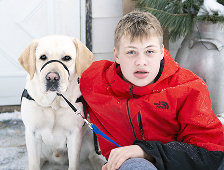 yellow Labrador and teenager boy sitting outside