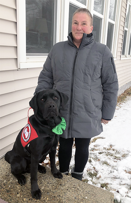 woman and large black service dog standing outside home