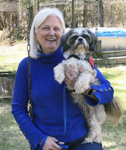 woman in sweater holding small dog outside