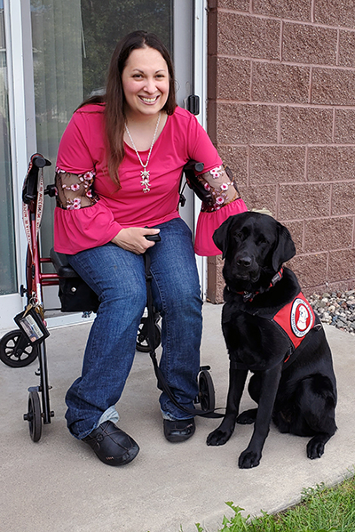 woman sitting in wheelchair next to service dog on outdoor patio