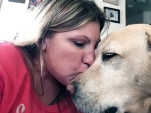 close-up of woman with eyes closed kissing yellow Lab dog on nose