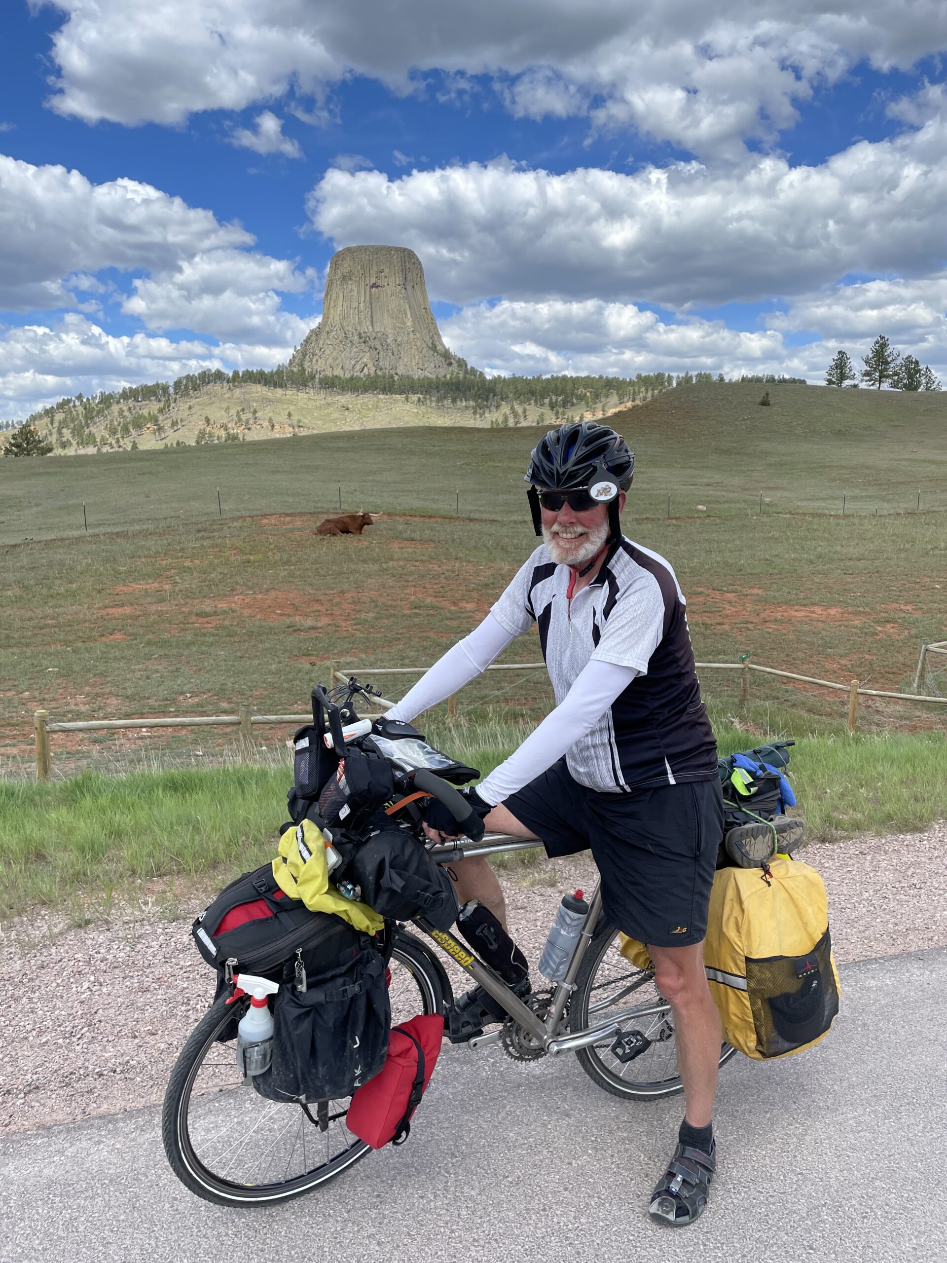 man in biking gear and helmet on stopped on bike on side of scenic road