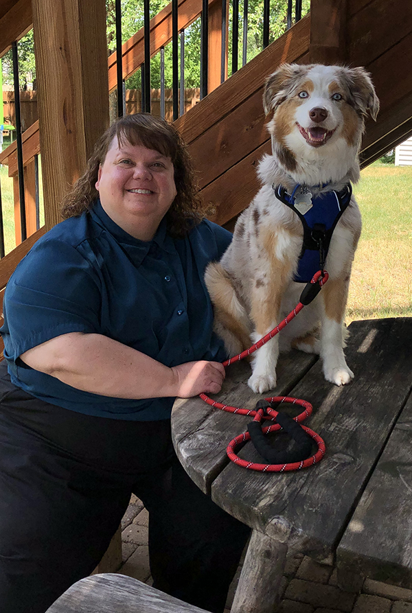 woman sitting at round picnic table with Australian Shepherd dog sitting on table next to her