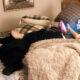 young boy lying on bed with black Lab dog