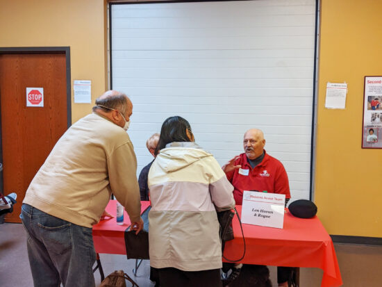 couple talking with man sitting at table under sign saying "Diabetes Assist Team"