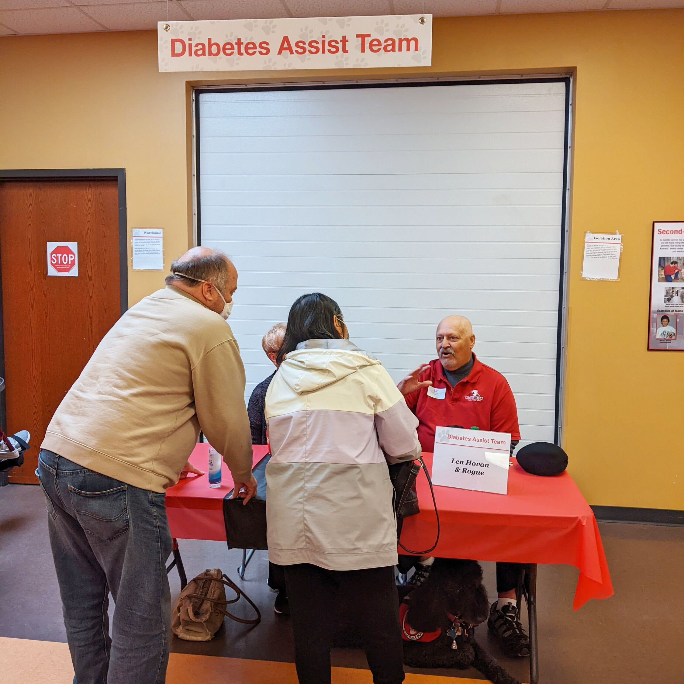 couple talking with man sitting at table under sign saying "Diabetes Assist Team"