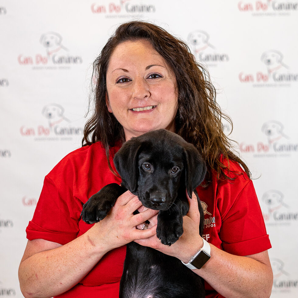 Jenny-Brisson-medium woman with long dark hair, holding black Lab puppy