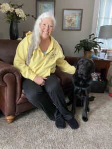 woman sitting in leather chair with black Lab sitting on floor in front of her