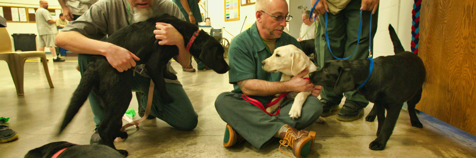 two inmates petting a couple of dogs