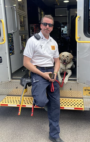 paramedic and yellow Labrador sitting on back of ambulance
