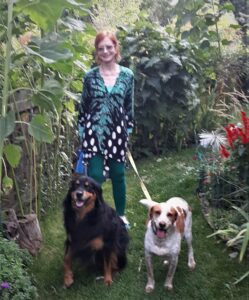 Woman standing with two dogs in lush greenery setting