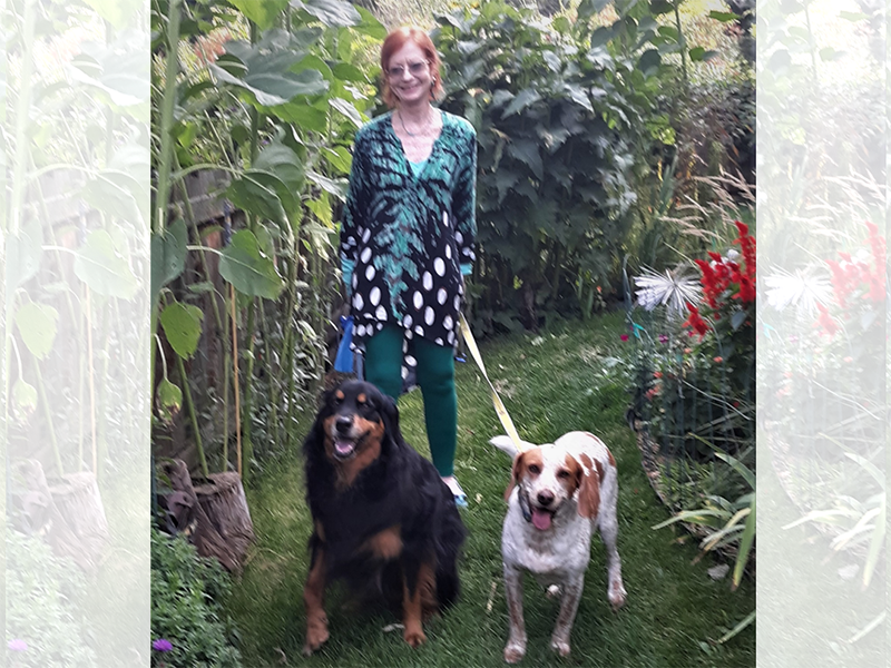 Woman standing with two dogs in lush greenery setting