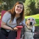 young woman sitting in wooden lawn chair with yellow Lab dog sitting on patio next to her