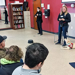 people in a classroom, with a speaker and service dog in front with a sign language interpreter