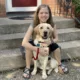 young woman sitting on front steps and hugging yellow Lab dog from behind