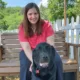 woman sitting on outside porch swing with black Lab dog sitting in front of her
