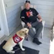 man sitting in rocker on porch with yellow Lab sitting in front of him wearing Can Do Canines service cape