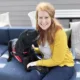 young woman sitting on outdoor sofa with black Lab service dog lying next to her