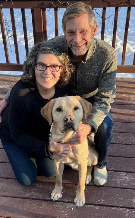 woman, man kneeling on deck with yellow Lab