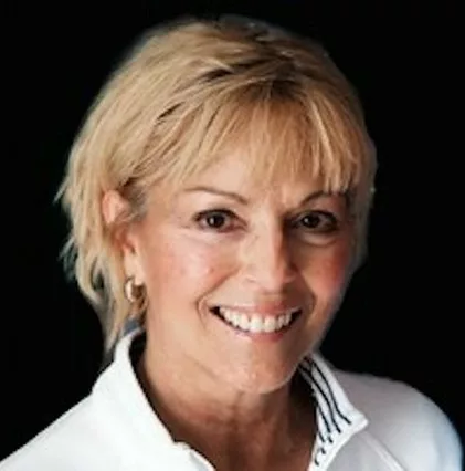 man with short blond hair, wearing white blouse smiling at camera