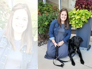 woman kneeling on sidewalk with black Lab dog lying next to her and both are looking at the camera