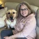 woman and yellow Lab sitting together on sofa and smiling at camera