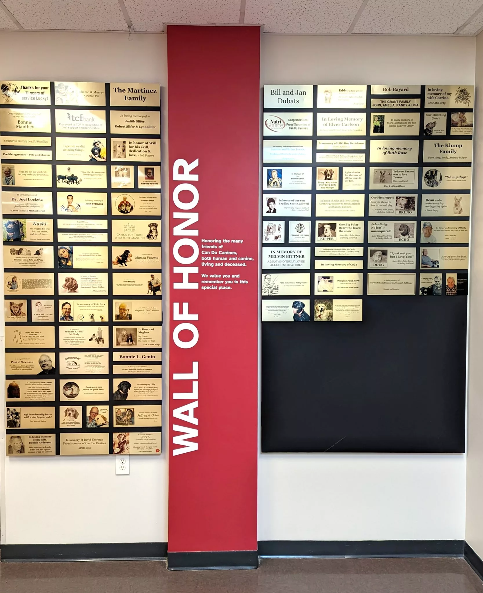 gold plaques mounted on black boards hung on wall with red pillar saying "Hallof Honor" between them