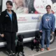 Two women and two black Labs standing in front of Can Do Canines transport van smiling at camera