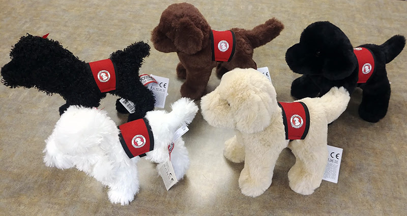 photo of 5 small stuffed animal dogs in various colors and wearing red Can Do Canines service cape