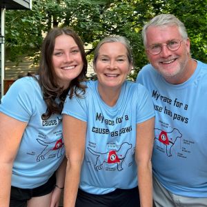 Two women and one man posing together in their blue race team shirts.