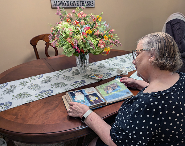 woman sitting at kitchen table looking through scrapbook of dogs