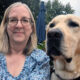 woman outside with arm around yellow Lab dog, smiling at camera