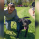 woman kneels next to her black Lab.