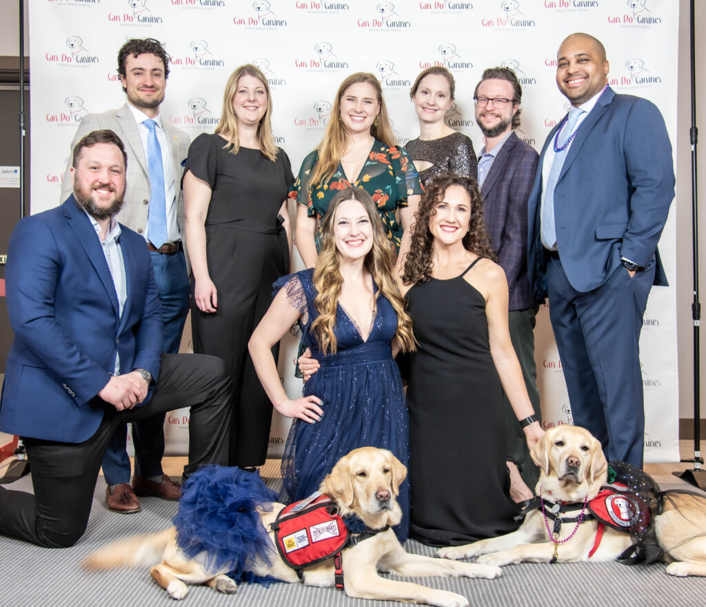 Group of people posing with two Can DO Canines Facility Dogs.